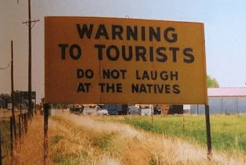 Cartel que indica en inglés a los visitantes, que no es necesario gritar a los nativos, para que les entiendan.